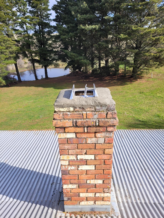 afterside view of repaired brick chimney and chimney dampner on tin roo