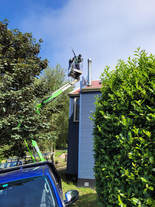 green cherry picker with worker repairing and cleaning repairing flue 